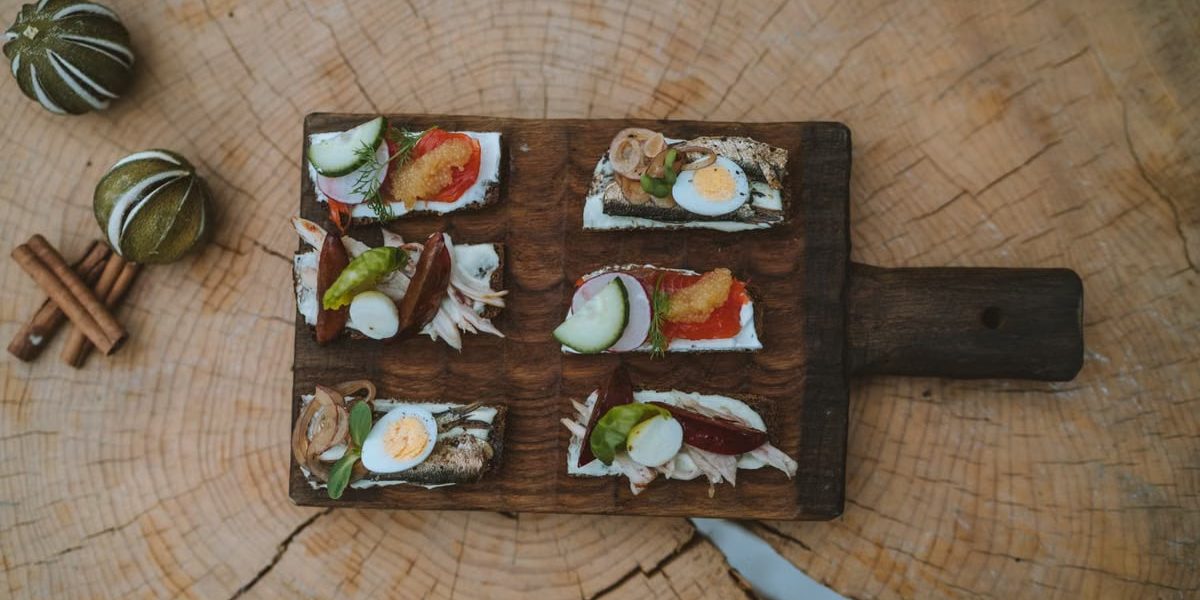Top view of holiday appetizers on a wooden board with festive elements, creating a cozy rustic feel.