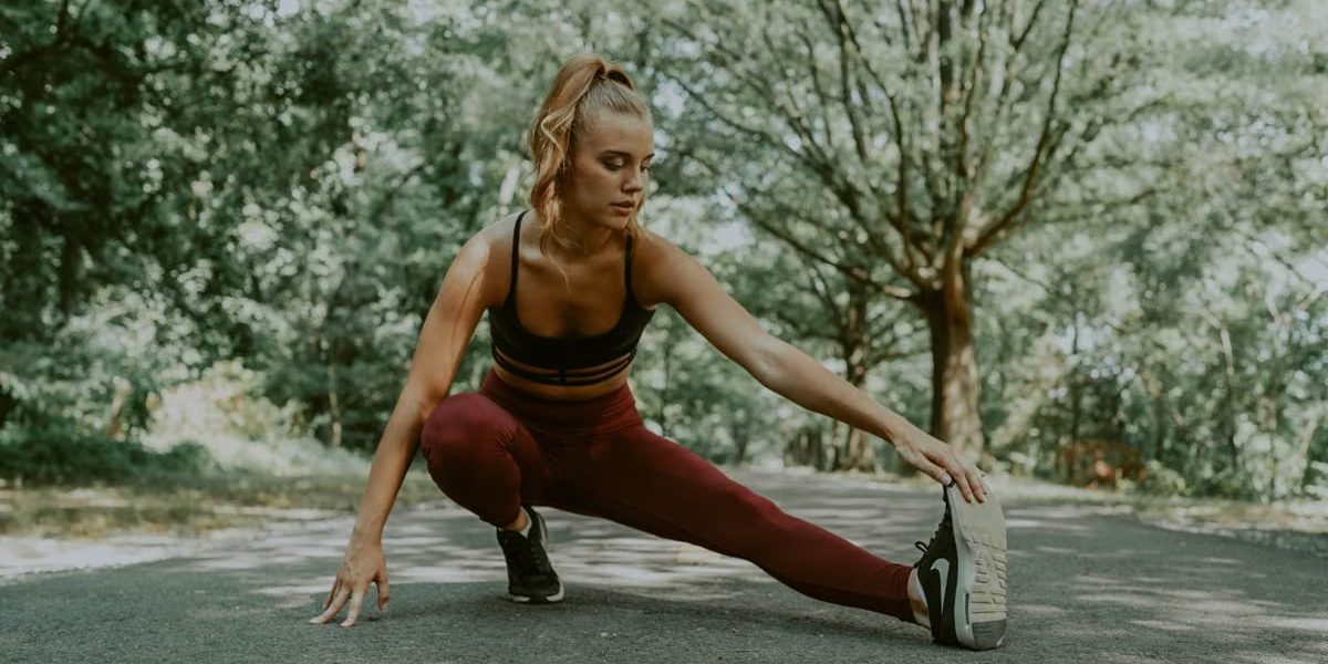 Full length of focused female athlete doing lunges forward while stretching legs in park