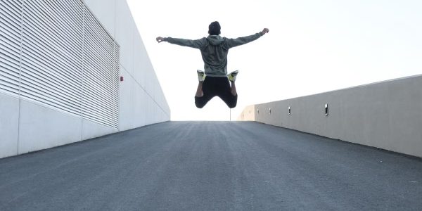 Man jumping on urban road with arms spread wide in Dubai, showcasing freedom and energy.